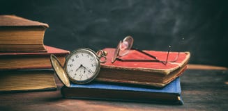 Винтажные книги и карманный вахта на темной предпосылке Стоковое фото RF Винтажные книги и карманный вахта на темной предпосылке Стоковое фото RF