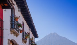 Внешний взгляд балкона с некоторыми цветками в баке старинного здания в главной улице города Антигуы с agua стоковое фото rf Внешний взгляд балкона с некоторыми цветками в баке старинного здания в главной улице города Антигуы с agua стоковое фото rf