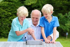 Внуки уча, что grandpa использовал ПК таблетки стоковые изображения rf Внуки уча, что grandpa использовал ПК таблетки стоковые изображения rf