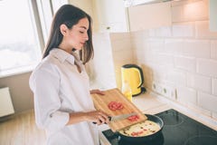 Внушительная молодая женщина варит завтрак в кухне Она кладет томаты отрезка в лоток с яичницами и грибами девушка стоковые фотографии rf Внушительная молодая женщина варит завтрак в кухне Она кладет томаты отрезка в лоток с яичницами и грибами девушка стоковые фотографии rf