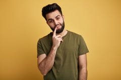 Внушительный приятный человек с пальцем на его рте смотря камеру стоковая фотография rf Внушительный приятный человек с пальцем на его рте смотря камеру стоковая фотография rf