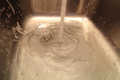 Вода бежать в кухонной раковине с пеной стоковое фото Вода бежать в кухонной раковине с пеной стоковое фото