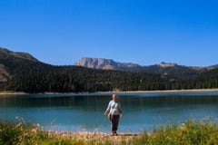 Вода бирюзы озера, соснового леса и гор Оглушать предпосылка с ликованием девушки природы туристским на пляже стоковая фотография Вода бирюзы озера, соснового леса и гор Оглушать предпосылка с ликованием девушки природы туристским на пляже стоковая фотография