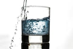 Вода льет по бокалам на белой предпосылке стоковое изображение rf Вода льет по бокалам на белой предпосылке стоковое изображение rf