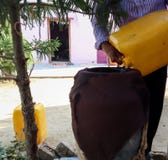 Вода человека лить от консервной банки в опарник стоковое фото rf Вода человека лить от консервной банки в опарник стоковое фото rf