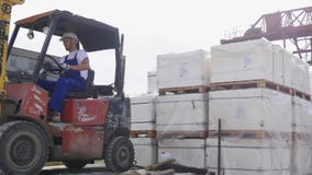Водитель платформы грузоподъемника в фабрике или складе управляя между строками Shelving с стогами коробок и упаковкой Водитель платформы грузоподъемника в фабрике или складе управляя между строками Shelving с стогами коробок и упаковкой