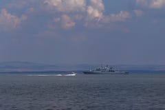Военный корабль плавает в воду на фоне драматического неба стоковые фотографии rf Военный корабль плавает в воду на фоне драматического неба стоковые фотографии rf