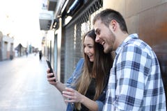 Возбужденные друзья находя удивительное содержание телефона в улице стоковое изображение Возбужденные друзья находя удивительное содержание телефона в улице стоковое изображение