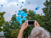 Воздушные шары гелия летают в небо и женщина фотографирует ее с мобильным телефоном стоковая фотография rf Воздушные шары гелия летают в небо и женщина фотографирует ее с мобильным телефоном стоковая фотография rf