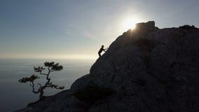 Воздушный силуэт молодой женщины взбираясь до верхней части горы перед морем Полет над дамой на видеоматериал Воздушный силуэт молодой женщины взбираясь до верхней части горы перед морем Полет над дамой на видеоматериал