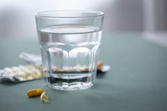 Волдырь 2 желтой медицины планшетов таблеток со стеклом воды стоковые фотографии rf Волдырь 2 желтой медицины планшетов таблеток со стеклом воды стоковые фотографии rf