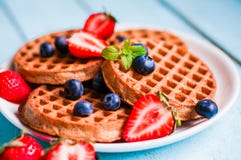 Все зерно waffles с ягодами на голубой деревянной предпосылке стоковые изображения Все зерно waffles с ягодами на голубой деревянной предпосылке стоковые изображения