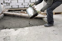 вспомогательный работник льет из цементного раствора ведра жидкостного на поле между полами дома стоковая фотография rf вспомогательный работник льет из цементного раствора ведра жидкостного на поле между полами дома стоковая фотография rf