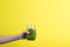 Встряхивание smoothie удерживания руки женщины против покрашенной стены Выпивая зеленая здоровая концепция smoothie стоковое изображение Встряхивание smoothie удерживания руки женщины против покрашенной стены Выпивая зеленая здоровая концепция smoothie стоковое изображение