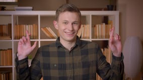 Всход крупного плана молодого привлекательного кавказского студента имея его пальцы пересек быть надеющийся смотрящ камеру внутри акции видеоматериалы Всход крупного плана молодого привлекательного кавказского студента имея его пальцы пересек быть надеющийся смотрящ камеру внутри акции видеоматериалы