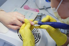 Выравнивание ногтей и обработка ногтей используя электрическую машину стоковая фотография rf Выравнивание ногтей и обработка ногтей используя электрическую машину стоковая фотография rf