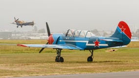 Голубое и красное воздушное судно тренера Yak-52 на том основании стоковые изображения Голубое и красное воздушное судно тренера Yak-52 на том основании стоковые изображения