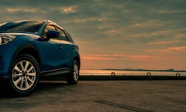Голубой компактный автомобиль SUV со спортом и современным дизайном припаркованный на конкретной дороге морем на заходе солнца в стоковые фото Голубой компактный автомобиль SUV со спортом и современным дизайном припаркованный на конкретной дороге морем на заходе солнца в стоковые фото