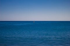 Голубой штиль на море против неба Горизонт Небольшая красная единственная надежда в море стоковое фото Голубой штиль на море против неба Горизонт Небольшая красная единственная надежда в море стоковое фото
