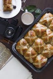 Горячие перекрестные плюшки с чашкой кофе, ручки циннамона на положении квартиры таблицы стоковые изображения Горячие перекрестные плюшки с чашкой кофе, ручки циннамона на положении квартиры таблицы стоковые изображения