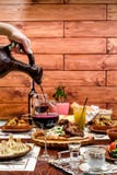 Грузинская национальная кухня девушка льет красное вино в стекле от керамического кувшина стоковое изображение Грузинская национальная кухня девушка льет красное вино в стекле от керамического кувшина стоковое изображение