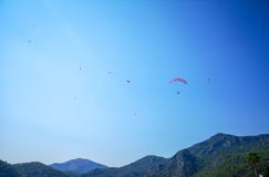 Группа в составе parachuters летая высоко над зеленым холмом в небе летнего времени голубом, Fethiye, Mugla стоковое изображение rf Группа в составе parachuters летая высоко над зеленым холмом в небе летнего времени голубом, Fethiye, Mugla стоковое изображение rf