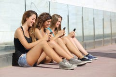 Группа в составе девушки подростка отправляя СМС на умном телефоне Группа в составе девушки подростка отправляя СМС на умном телефоне