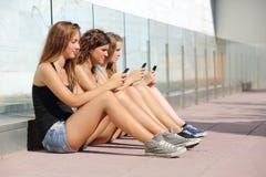 Группа в составе 3 девушки подростка печатая на мобильном телефоне Группа в составе 3 девушки подростка печатая на мобильном телефоне