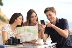 Группа в составе молодые туристские друзья советуя с gps составляет карту в умном телефоне Группа в составе молодые туристские друзья советуя с gps составляет карту в умном телефоне