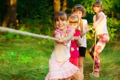 Группа в составе счастливые дети играя перетягивание каната снаружи на траве Веревочка детей вытягивая на парке Летнего лагеря стоковое фото rf Группа в составе счастливые дети играя перетягивание каната снаружи на траве Веревочка детей вытягивая на парке Летнего лагеря стоковое фото rf