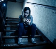Грустная подавленная несчастная девушка подростка страдая от cyberbullying мобильным умным телефоном сидя самостоятельно стоковая фотография rf Грустная подавленная несчастная девушка подростка страдая от cyberbullying мобильным умным телефоном сидя самостоятельно стоковая фотография rf