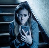 Грустная подавленная несчастная девушка подростка страдая от cyberbullying мобильным умным телефоном сидя самостоятельно стоковое фото rf Грустная подавленная несчастная девушка подростка страдая от cyberbullying мобильным умным телефоном сидя самостоятельно стоковое фото rf