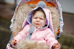 Грустный плача маленький красивый ребенок сидя в pram или прогулочной коляске на день осени Несчастный уставший и вымотанный ребе стоковые изображения rf Грустный плача маленький красивый ребенок сидя в pram или прогулочной коляске на день осени Несчастный уставший и вымотанный ребе стоковые изображения rf