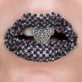 Губы творческого макияжа макроса и конца-вверх красивые женские с черными и серебряными драгоценными камнями и сердце в открытом стоковое изображение rf Губы творческого макияжа макроса и конца-вверх красивые женские с черными и серебряными драгоценными камнями и сердце в открытом стоковое изображение rf