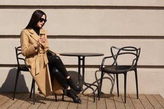 Дама брюнета красивая молодая сидит на террасе, выпивает ароматичный горячий кофе, имеющ бежевый и черный взгляд Привлекательная стоковые фото Дама брюнета красивая молодая сидит на террасе, выпивает ароматичный горячий кофе, имеющ бежевый и черный взгляд Привлекательная стоковые фото