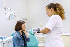 Дантист говоря с пациентом женщины в зубоврачебном стуле Женский доктор с рентгеновским снимком принимает диагноз и рекомендует о стоковая фотография rf Дантист говоря с пациентом женщины в зубоврачебном стуле Женский доктор с рентгеновским снимком принимает диагноз и рекомендует о стоковая фотография rf