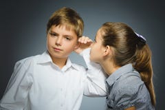 Девочка-подросток шепча в ухе мальчика на серой предпосылке черный телефон приемника принципиальной схемы связи Стоковые Фото Девочка-подросток шепча в ухе мальчика на серой предпосылке черный телефон приемника принципиальной схемы связи Стоковые Фото