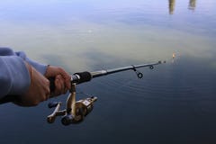 Девушка держа рыболовную удочку с 2 руками для того чтобы уловить рыб в теплом вечере стоковое фото rf Девушка держа рыболовную удочку с 2 руками для того чтобы уловить рыб в теплом вечере стоковое фото rf