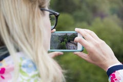 Девушка держа телефон для того чтобы сфотографировать взгляд ландшафта стоковое фото rf Девушка держа телефон для того чтобы сфотографировать взгляд ландшафта стоковое фото rf