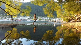 Девушка идя через небольшое реку во время осени в Queenstown, Новой Зеландии стоковое фото Девушка идя через небольшое реку во время осени в Queenstown, Новой Зеландии стоковое фото