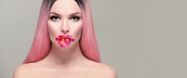 Девушка модели красоты с розовым цветком в ее рте Женщина красивой весны молодая романтичная с розовый представлять волос стоковая фотография rf Девушка модели красоты с розовым цветком в ее рте Женщина красивой весны молодая романтичная с розовый представлять волос стоковая фотография rf