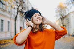 Девушка молодого милого битника предназначенная для подростков в музыке черной шляпы слушая через наушники на улице осени стоковое фото Девушка молодого милого битника предназначенная для подростков в музыке черной шляпы слушая через наушники на улице осени стоковое фото