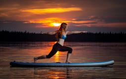 Девушка работая йогу на paddleboard в заходе солнца на сценарном озере Velke Darko стоковые изображения rf Девушка работая йогу на paddleboard в заходе солнца на сценарном озере Velke Darko стоковые изображения rf