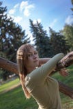 Девушка с пропуская стойками волос около дерева на предпосылке елей стоковая фотография Девушка с пропуская стойками волос около дерева на предпосылке елей стоковая фотография