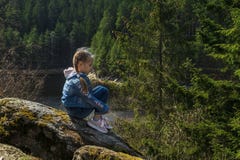 Девушка сидит на скале и взглядах на природе, девушке сидя на утесе и наслаждаясь взглядом долины стоковая фотография Девушка сидит на скале и взглядах на природе, девушке сидя на утесе и наслаждаясь взглядом долины стоковая фотография