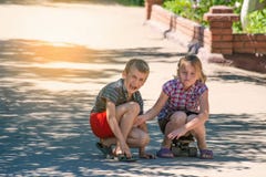 Девушка чувствует к сожалению для мальчика, ее брата, который был ранен пока едущ скейтборд на дороге в улице стоковая фотография rf Девушка чувствует к сожалению для мальчика, ее брата, который был ранен пока едущ скейтборд на дороге в улице стоковая фотография rf