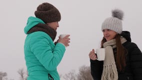 Девушки, который замерли в холодных говоря и выпивая горячих пить от стекел смеются над усмехаться стоковое фото rf Девушки, который замерли в холодных говоря и выпивая горячих пить от стекел смеются над усмехаться стоковое фото rf
