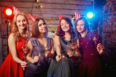 Девушки для вечеринки по случаю дня рождения в крышках на их головах и с бенгальскими огнями их руки стоковые фото Девушки для вечеринки по случаю дня рождения в крышках на их головах и с бенгальскими огнями их руки стоковые фото