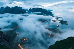 Деревня Reine в облаках и тумане в раннем утре Света в ноче, Норвегия Lofotens стоковые фотографии rf Деревня Reine в облаках и тумане в раннем утре Света в ноче, Норвегия Lofotens стоковые фотографии rf
