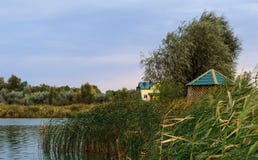 деревянная кабина около края малых малых реки или пруда между сочной листвой приближая к заходу солнца стоковые фотографии rf деревянная кабина около края малых малых реки или пруда между сочной листвой приближая к заходу солнца стоковые фотографии rf